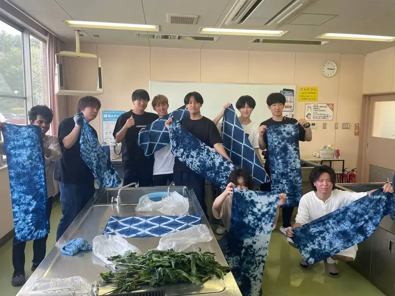 藍染めの布を掲げる参加者たち